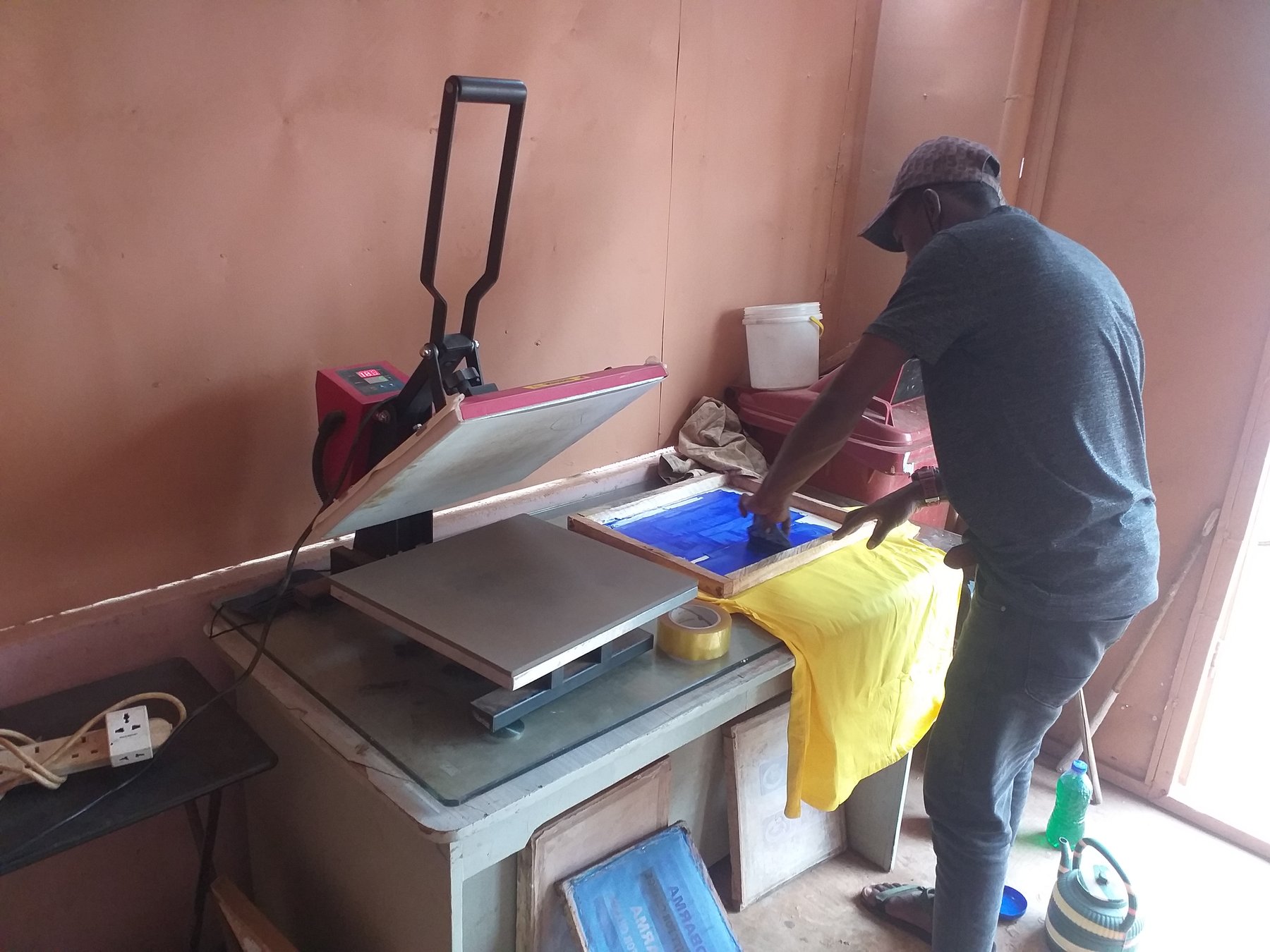 Heat press clamping a freshly printed textile in a studio
